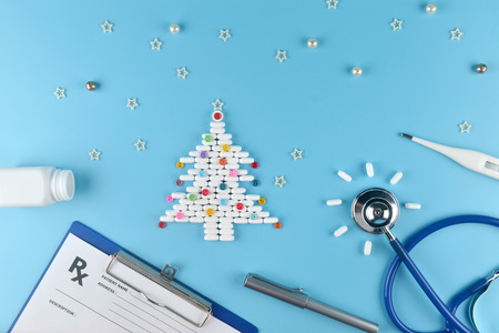 Medicine pills shape of christmas tree and others equipment of doctor on blue background. Concept christmas and new year.の写真素材