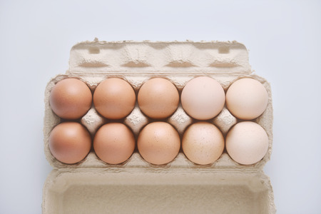 Chicken eggs are arranged in a gradient color tone in eco carton on white background.(top view)の写真素材