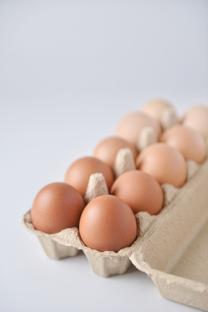 Chicken eggs are arranged in a gradient color tone in eco carton on white background.(perspective view)の写真素材