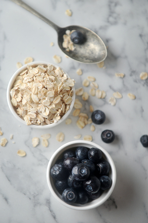 A fresh blueberries and Organic rolled oats in bowl, on marble background. Concept of cooking ingredients, decorate bakery, healthy eating and nutrition.の写真素材