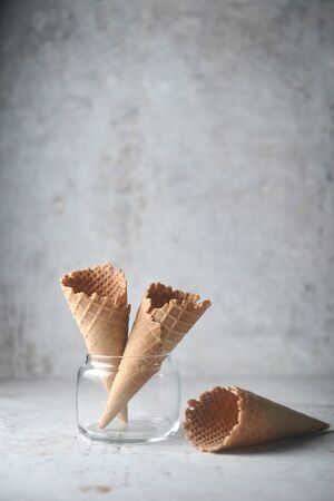 waffle cone stand in glass and spread on ground on concrete background.