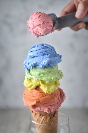 Putting strawberry ice cream on top rainbow ice cream.の写真素材