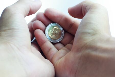 Ten Baht Thailand coins with the king in his hand.