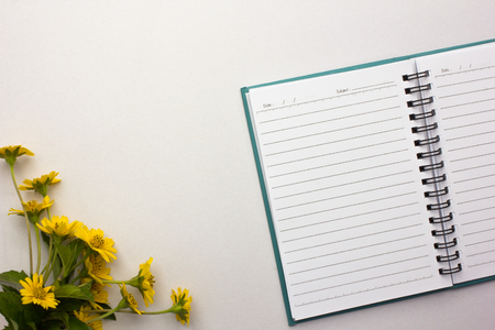 Note placed on a white background with yellwe flowerの写真素材