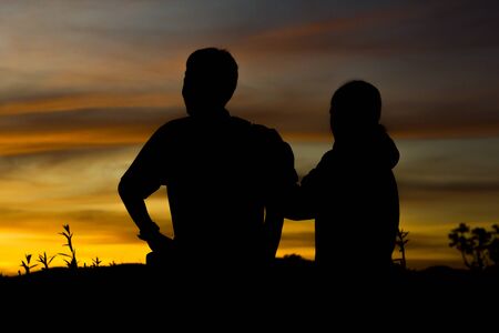 Man and two women stood watching the sunset.の写真素材