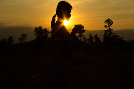 Woman  drinking cup of hot tea or coffee outdoors in sunlightの写真素材