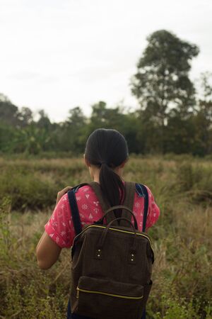travel, hiking, backpacking, tourism and people concept - happy with backpacks walking along farm.の写真素材