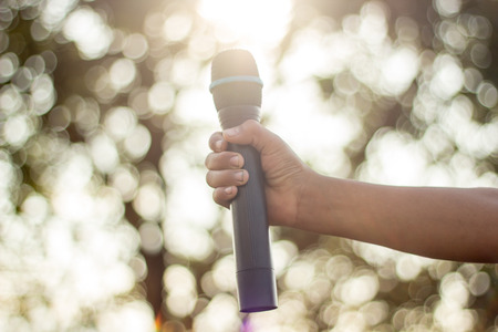 hand holding a single microphone against colourful background,singing contest.の写真素材