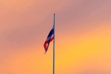Flag on flag pole, background orange sky.の写真素材