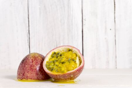 Passion fruits half and juice with leaves on the vintage wooden background. Closeup, Select focus.