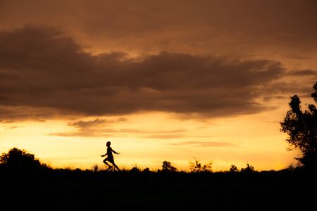 silhouette of a Boy playing on the sunset background.の写真素材