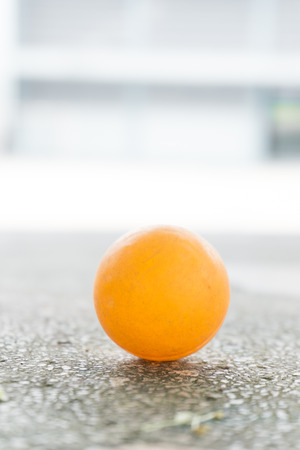 Orange table tennis ball on the floor.