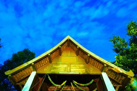 Buddha in the arch with ornamental flowers at night.の写真素材