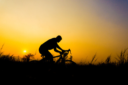 Silhouette of cyclist with friend in motion on the background of beautiful sunset.の写真素材