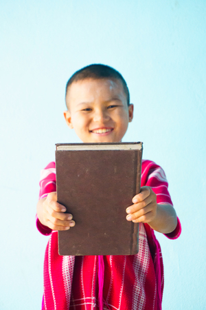 Little boy holding a large book on a light blue background.の写真素材