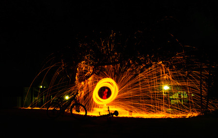 Burning steel wool spinned in the forest. Showers of glowing sparks from spinning steel wool.の写真素材