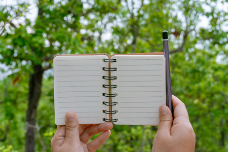 Hold a notebook with a pencil.  With space for text inputの写真素材