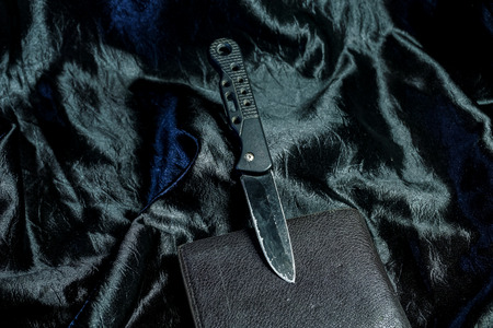 The old black folding knife on the black fabric is shiny.
