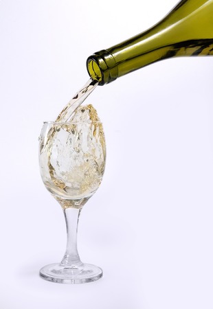 white wine pouring from bottle into glass isolated on white backgroundの写真素材
