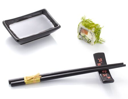 Sushi roll with black ceramic plate with soy sauce and black chopsticks isolatedの写真素材