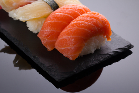 Sushi nigiri set on a stone plate over black backgroundの写真素材