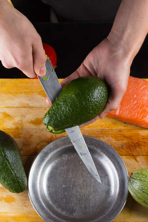 chef slicing the avocado closeup on a wooden board