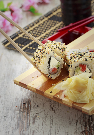 Japanese cuisine. Sushi set and one peace of roll in chopsticks.の写真素材