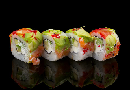 Japanese cuisine. Sushi roll with salmon avocado and tobiko over black background.の写真素材
