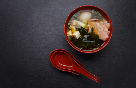 Japanese miso soup in a red bowl on the table.の写真素材