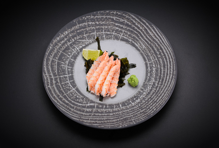 Japanese cuisine. Sushi. Shrimp sashimi on a round plate with lime and wasabiの写真素材