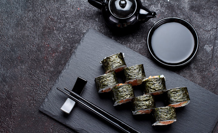 Japanese cuisine. Sushi roll on a stone plate and dark concrete background. Top view.の写真素材