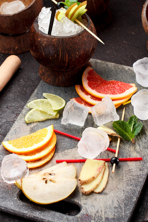 Coconut with ice and fresh fruits (grapefruit, kiwi, orange ) and mint over concrete background.の写真素材