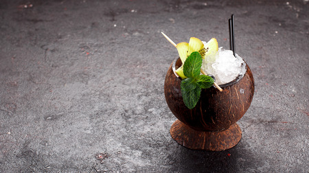 Coconut cocktail with fruits and ice over concrete backgroundの写真素材