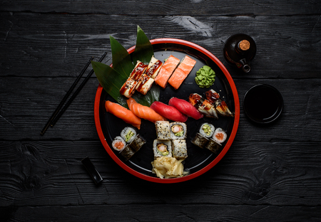 Japanese cuisine. Sushi set on a round plate over dark wooden background.の写真素材