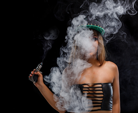 Sexy girl is vaping an e-cigarette. Black background.の写真素材