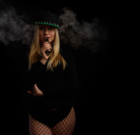 Young sexy woman is vaping. Studio shoot. E-cigarette. Smoke.の写真素材