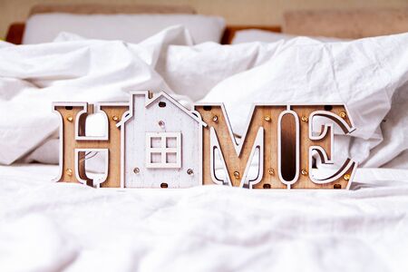 COVID-19 Coronavirus stay home save lives viral social media message sign with text for social distancing awareness. Staying at home concept. Wooden house inscription home on bedの写真素材