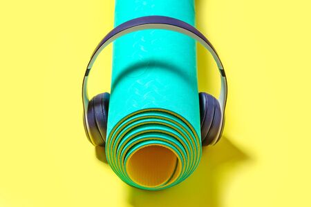 Flat Lay Sport and fitness equipment, headphones and mint yoga mat listen music on yellow background. Top viewの写真素材