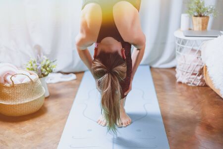 Close up Young attractive sporty woman practicing yoga, standing forward bend exercise, head to...