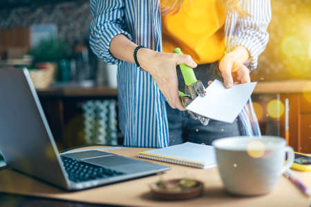 DIY Home office woman and distance learning online education handmade. Cropped lady girl scrapbook and craft and working with notebook in kitchen and drinking coffee at home. Using computer.の写真素材