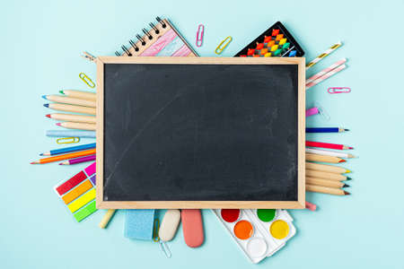 Concept Back To School Color Chalk Pencil Notebook Stationery on blue Blackboard Background. Design...