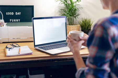 Cropped woman typing on laptop computer while sitting at home. Close up hands with mockup monitor...