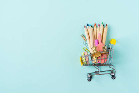 Buying school supplies, pencils, tape, notebook and crayons. Stationery for kids in a shopping cart...