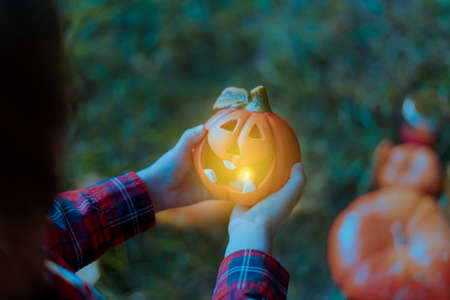 Kid's hand holding Jack'O pumpkin lamp, trick or treat on Halloween day. Concept for autumn holidays background.の写真素材