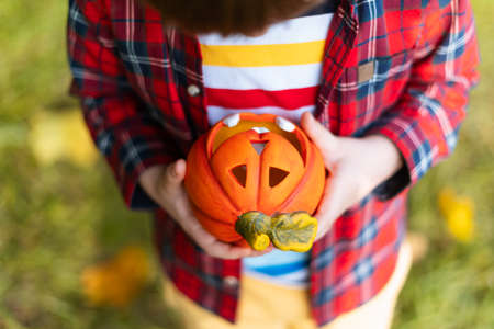 Kid's hand holding Jack'O pumpkin lamp, trick or treat on Halloween day. Concept for autumn holidays background.の写真素材