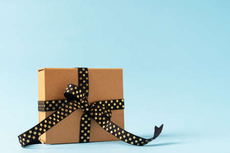 Christmas Gift box or present box with black golden ribbon on blue background