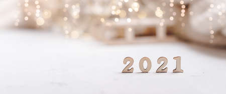 Christmas background or greeting card with 2021 wooden text and copy space. Glowing snow bokeh....