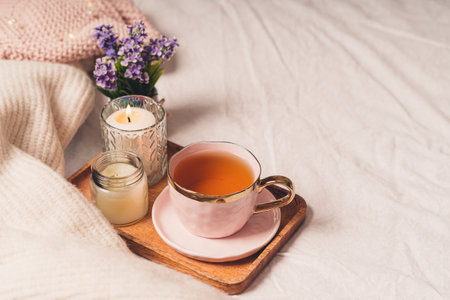 Details of still life in the home interior of living room. Sweater, cup of tea, cotton, cozy, book, candle. Moody. Cosy autumn winter concept. Decoration, vintage with glow bokeh.の写真素材