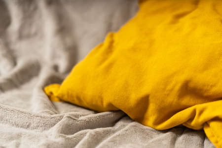 Gray knitted plaid and yellow pillow on trendy background with copy space. Illuminating Yellow and Ultimate Gray, new colors of the year 2021.の写真素材