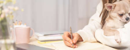Distance learning online education and work. Business woman with puppy dog writes goals, plans, make...